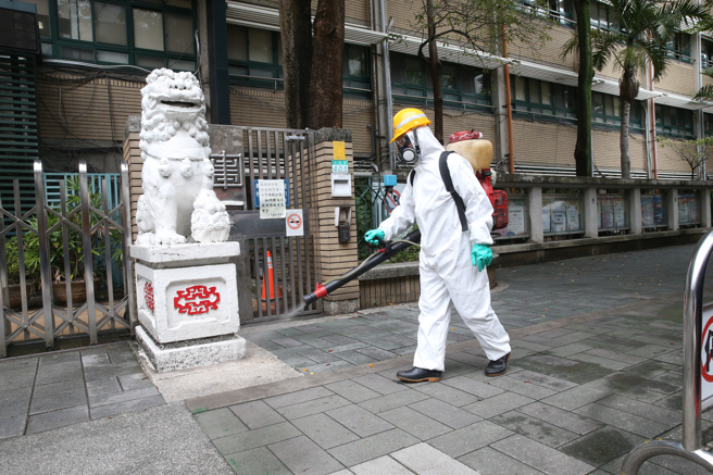 國內不明感染源確診增加，環保局清潔人員在校園周邊噴灑消毒藥水。（陳君瑋攝）