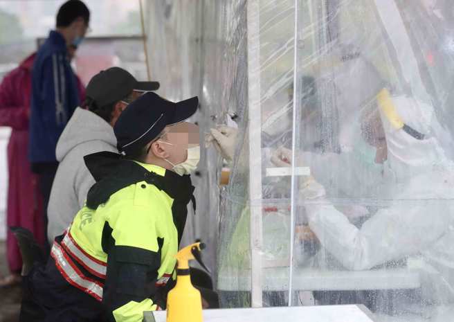 中央流行疫情指揮中心公布，今日新增9例與基隆群聚案件有關，其中6例為基隆本土個案，包括警察1例、銀河小吃店消費者一家3口、接觸者1例、感染源不明1例。圖為基隆員警進行採檢。（非當事人，中央社資料照）