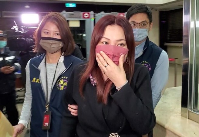 台北市殡葬管理处副处长王文秀（红色口罩者），被检举涉嫌于2020年至2021年间泄漏殡葬处採购奠祭、礼厅布置标案资讯，护航特定厂商得标，涉嫌违反《贪污治罪条例》图利罪等罪，台北地检署约谈王文秀等12名官商到案，检方讯后29日对王女声押禁见，台北地院裁定王女以60万交保。（中央社）