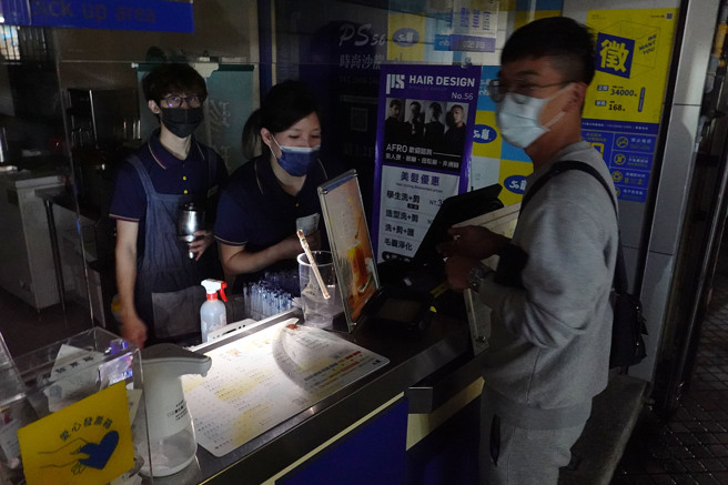 台北市士林捷运站附近商圈30日晚间发生停电状况，饮料店工作人员用微弱的手机灯光为顾客点餐。（姚志平摄）