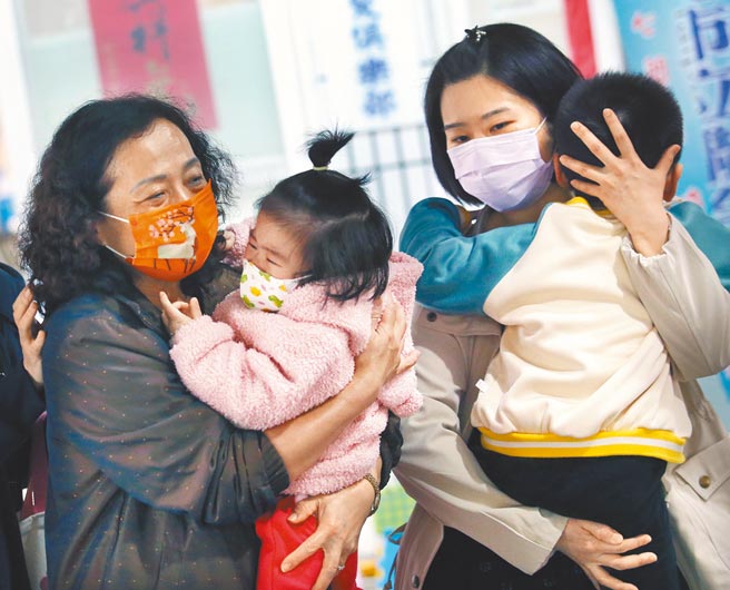 新北市中和区某社区大楼住户惊传6例新冠肺炎确诊个案，附近民眾29日前往快筛站採检，两名幼童无法忍受筛检时的不适感嚎啕大哭，家人赶紧安抚情绪。（范扬光摄）