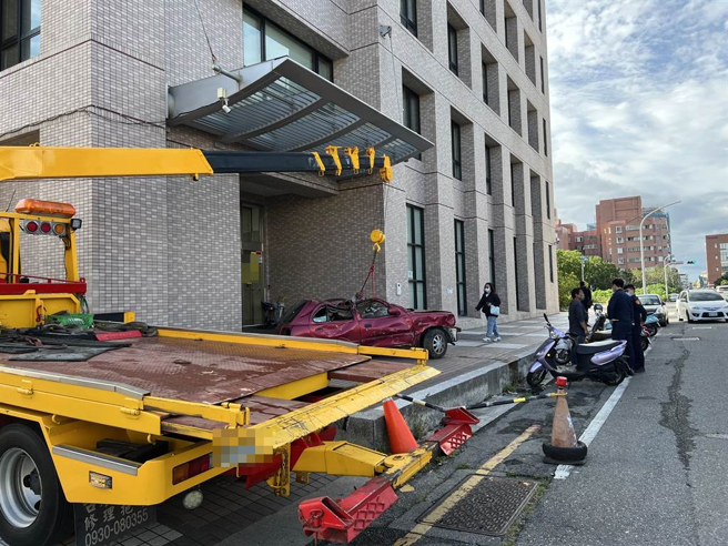 台東民眾因不滿保險公司理賠刻意刁難，31日特地以拖吊車將廢棄車輛擋在保險公司門口。（蔡旻妤攝）