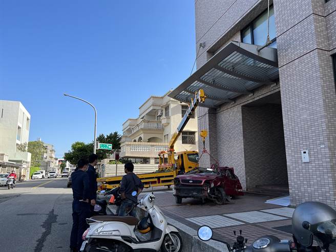 台東民眾因不滿保險公司理賠刻意刁難，31日特地以拖吊車將廢棄車輛擋在保險公司門口。（蔡旻妤攝）