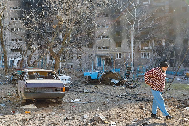 烏克蘭武裝部隊總參謀部昨痛批俄羅斯撤軍只是詭計，研判可能只是個別部隊的「輪調」，意在誤導烏克蘭軍方。圖為烏克蘭馬里烏波爾當地居民走過損毀的建築。    （新華社）