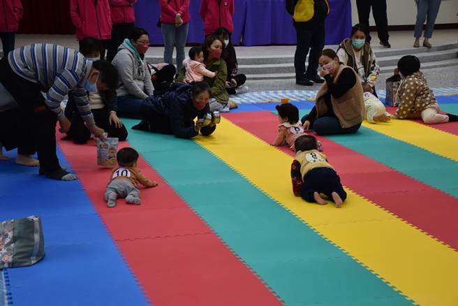 兒童嘉年華並舉辦嬰兒爬行比賽，家長卯足全力吸引小寶貝往前爬。（謝明俊攝）