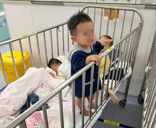 多张照片显示，隔离点内有许多带铁栏的婴儿床，有三名婴儿挤在一张床上，其中一个孩子的头被床单盖住；旁边的床上至少有三名幼儿，有的躺着，有的扶着床栏站着，十分拥挤。（大陆民眾微信截图）