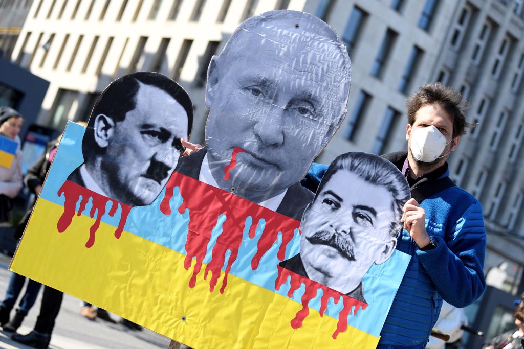 抗议人士手拿印有俄罗斯总统普丁（Vladimir Putin）及前苏联独裁者史达林（Joseph Stalin）图像的海报。图/路透社(photo:ChinaTimes)