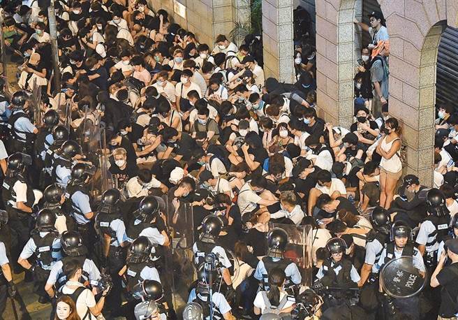 2019年10月1日香港「反送中運動」期間，其中一批抗議示威民眾在黃大仙非法集結、堵路，以及投擲汽油彈、磚頭和縱火燒車，香港法官4日終判處其中3被告分別入獄4年3個月至4年6個月，另兩人則分判入勞教中心及教導所。圖為2019年6月10日香港警方深夜採取行動，拘押過百名示威者。（中新社）