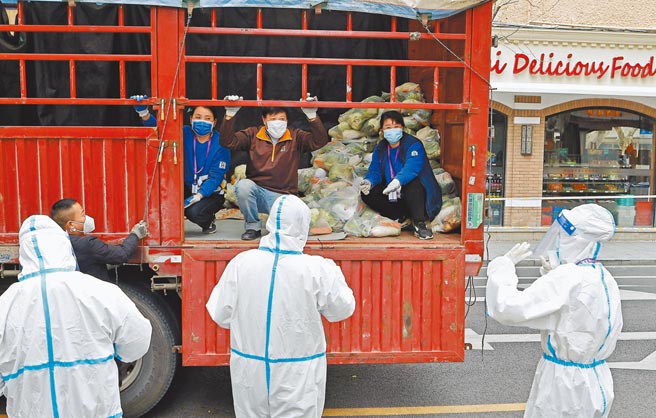 上海疫情严峻，持续封控，有主妇面临断粮危机，焦虑不安。图为工作人员在上海社区门口与送货人员交接物资。（中新社）