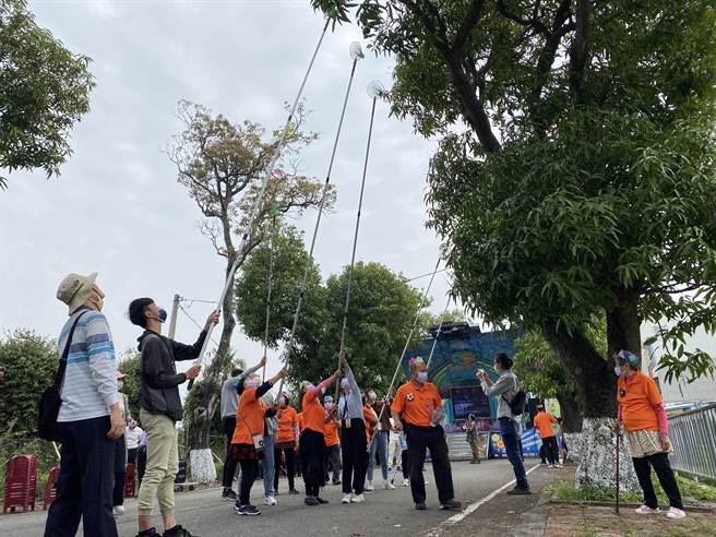 中正大学重构大学路计画「烈风光影户外照片展」7日上午开展，丰收社区长辈跟中正大学同学一起「打芒果」，重温过去回忆。（张亦惠摄）