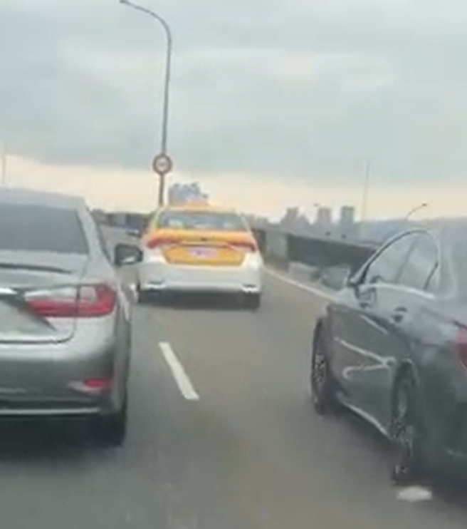 一名運將疑身體不適，行經環河北路高架橋時，車子左右搖晃，後方來車因不敢超越造成堵塞。(翻攝自影片)
