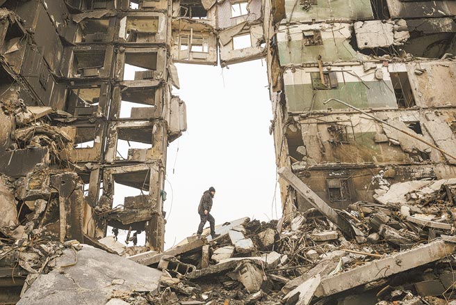 一名乌克兰居民5日在一栋遭战火袭击的公寓楼里寻找物品。（美联社）