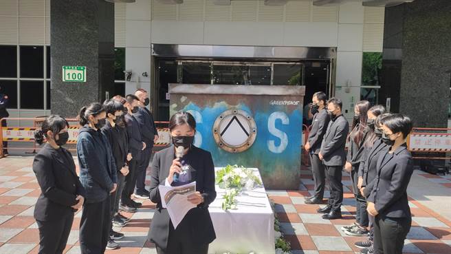 绿色和平今天在渔业署前设置漆上「SOS」的仿制船舱及置满白色鲜花的棺材，为无辜往生的渔工送别，并祈祷如强迫劳工等类似的憾事勿再发生。（林良齐摄）