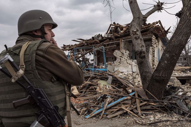俄军入侵乌克兰，1名乌军日前站在被摧毁的民宅前。（路透）