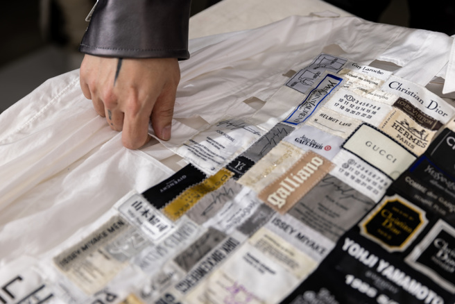 周裕穎將各時尚品牌不同年代的標籤拼貼在白色襯衫上，體現「升級再造」的精神，也饒富視覺趣味。（攝影／林冠良）