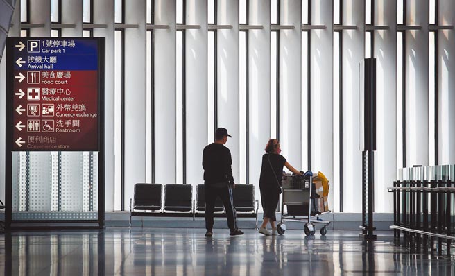 随着本土疫情再次爆发，即将在6月底届满的《防疫纾困特别条例》是否将延长？行政院长苏贞昌昨表示，因为疫情到6月不会戛然停止，所以大概会往延长的方向走。图为桃园机场第一航厦内，两名旅客走过空荡荡的出境大厅。（范扬光摄）