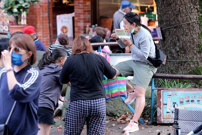 也有民眾买了小吃，迫不急待脱下口罩就坐在路边吃将起来。（黄世麒摄）