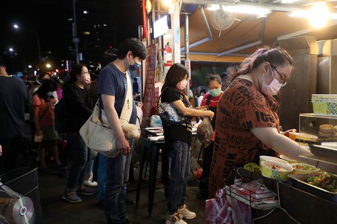 民眾到夜市品尝美食，除了饮食外都戴上口罩，做好自身防护。图为店员们戴着口罩帮外带的客人准备餐点。（刘宗龙摄）