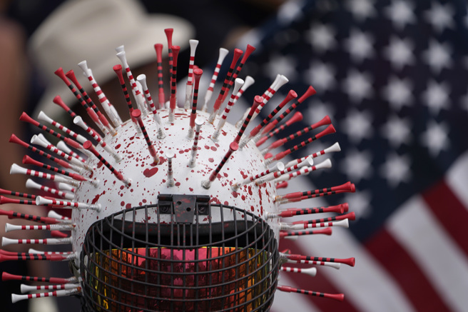 美國加州洛杉磯市政府準備制訂有關強制接種疫苗的法案，遭到不少民眾到市政廳外抗議。 圖為抗議人士設計插滿注射針的頭盔。（圖／美聯社）