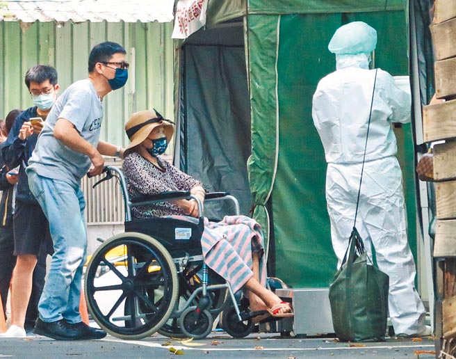 新北13日新增264例确诊，人数仍居各县市之冠。一早位于永和的耕莘医院筛检站，一位民眾推着坐轮椅的长者前来做PCR筛检。（粘耿豪摄）