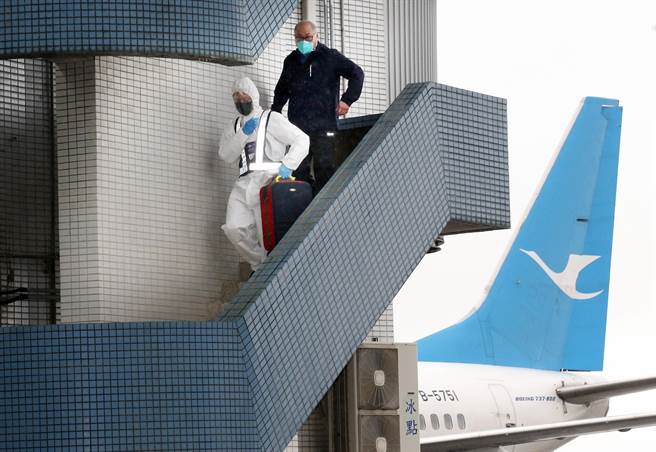 台湾NGO工作者李明哲（右）15日上午搭机返台，班机靠桥后在航务人员陪同下，从空桥直接走下机坪。（范扬光摄）