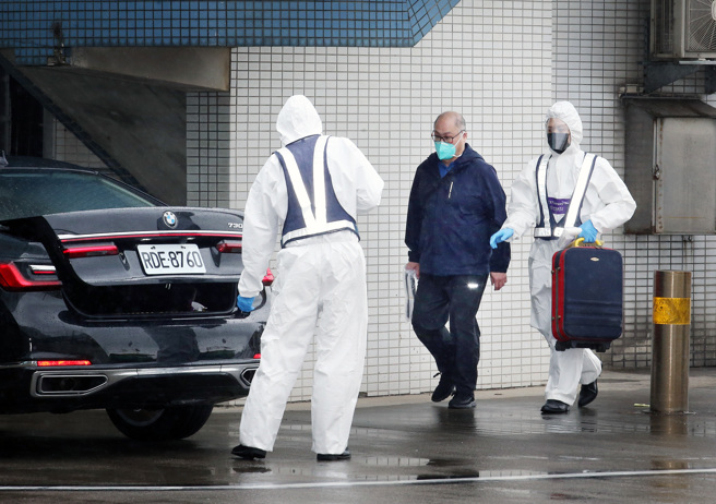 台湾NGO工作者李明哲（中）15日上午搭机返台，班机靠桥后在商务中心人员陪同下，从空桥直接走下机坪搭车离开。（范扬光摄）