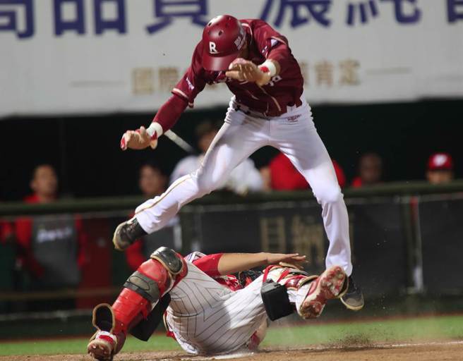 中華職棒15日味全龍對樂天桃猿之戰，桃猿陳晨威7局上藉著安打自2壘直闖本壘，跳在空中企圖躲開接球飛撲欲觸殺的味全捕手吉力吉撈未成，掉落在吉力吉撈的身上遭到觸殺出局。（鄭任南攝）