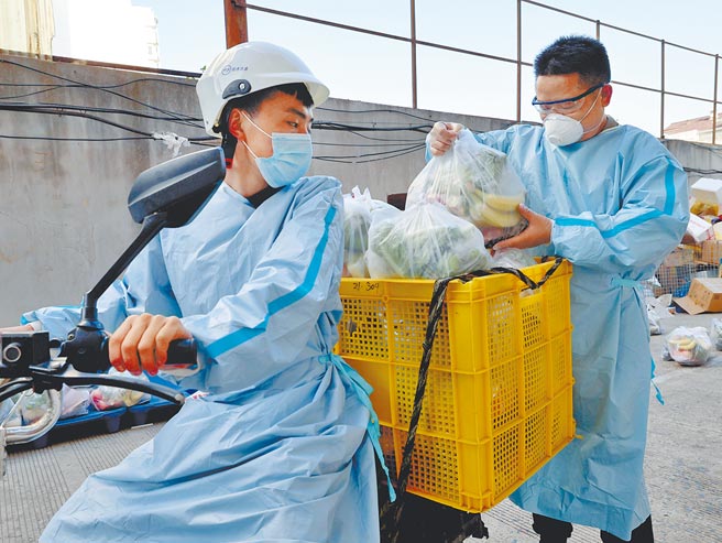 目前上海最缺的就是物流體系的從業人員，圖為大陸圓通速遞上海長寧區福泉分公司經理蔡小兵（右）幫投遞員王斌裝貨。每天處理物資平均在14噸左右。（新華社）