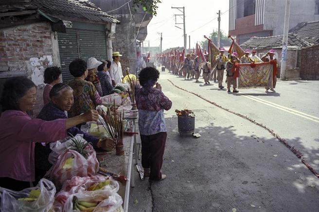 媽祖信仰深入民間，每個時代都留下信徒虔誠為媽祖祝壽的影像。圖為1999年，信眾守在大甲媽祖遶境進香的途中。（外交部資料）