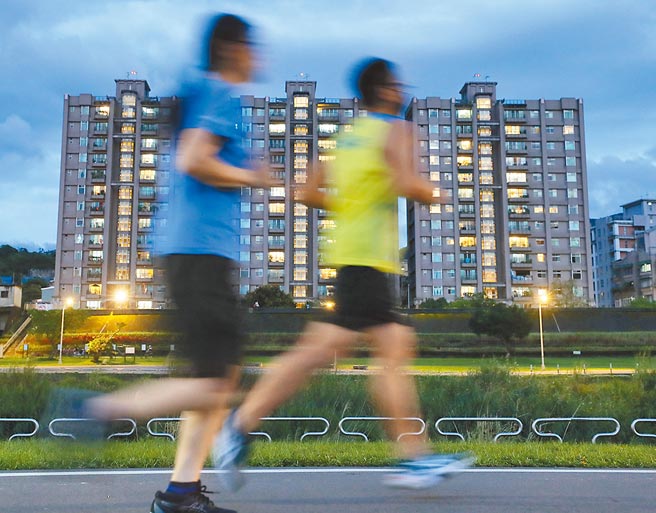 國發會主委龔明鑫表示，隨裝置容量擴充、技術進步，再生能源的成本長期來看會下降。圖為跑者經過亮燈的大樓。（季志翔攝）