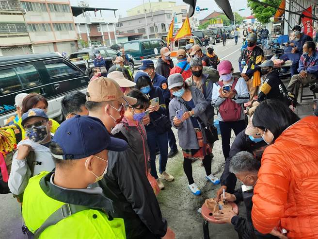 大甲媽的信眾拿進香帽，排隊請鎮瀾宮董事長顏清標簽名，顏清標坐在路旁忙的不可開交。（民眾提供）