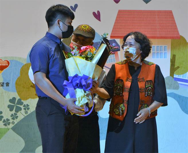 牧師吳榮標（中）與妻子范金珠（右）從事寄養家庭服務20年，17日獲頒榮退獎牌時，曾受照顧的孩子阿和（左）驚喜現身道賀。（謝佳潾攝）