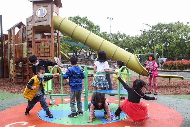 本土新冠肺炎疫情升温，甚至出现首例幼儿重症个案，卫福部食药署今召开专家会议审查儿童疫苗，核准6至11岁儿童可接种莫德纳疫苗。适逢周末假日，台北市大安森林公园内，小朋友戴口罩玩游乐器材。（邓博仁摄）