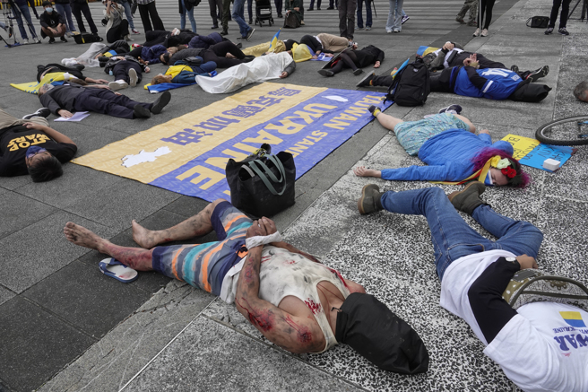 在台乌克兰人及声援团体17日在台北自由广场前举行集会，参与人士躺在地上共同演出集体死亡行动剧，控诉俄罗斯部队入侵乌克兰后屠杀平民的暴行。（黄子明摄）