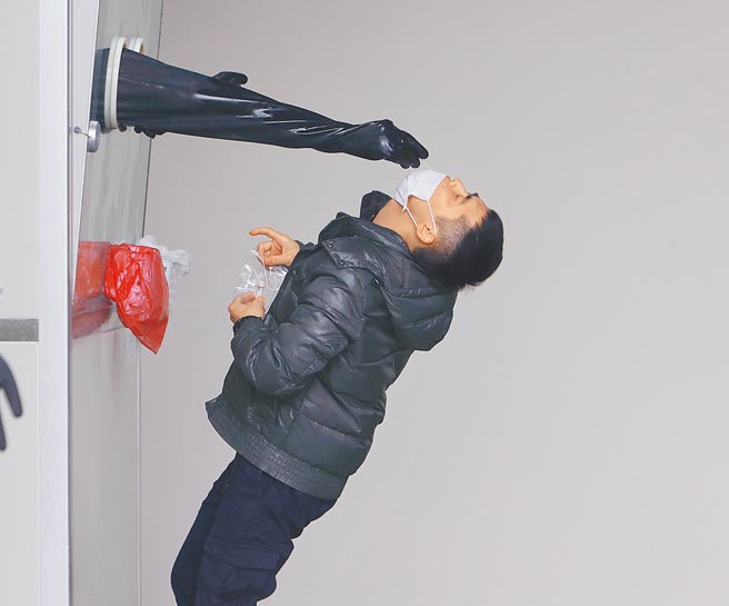 新北市市立土城医院社区筛检站，1名民眾难耐筛检的刺痛，因反应太及出现闪躲后仰的画面。就有民眾说如果有家用快筛试剂，就能先在家採检，会方便许多。（陈怡诚摄）