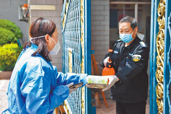上海某封控區小區門口，應急配送專車的配送員田丹通過小區保安把兒童藥品送給收貨人。（中新社）