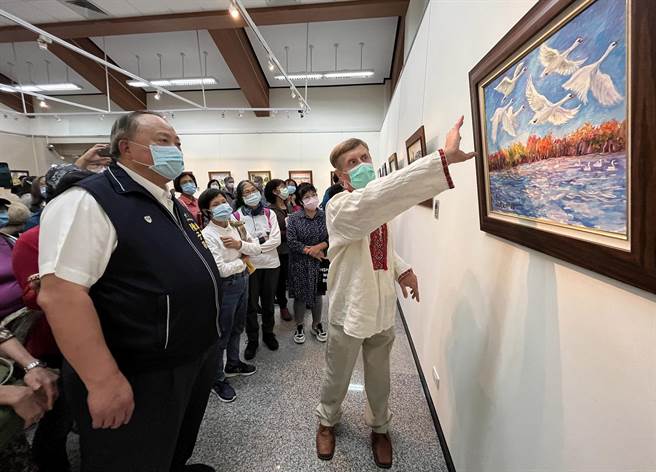 烏克蘭畫家伊凡（右一）向民眾解說他的作品。（台中市港區藝術中心提供）