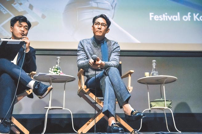 李政宰在「韩国电影节」活动中表情认真而愉悦，穿Gucci黑色皮鞋混搭灰毛衣加蓝格子裤，很有自己的一套。（CFP）