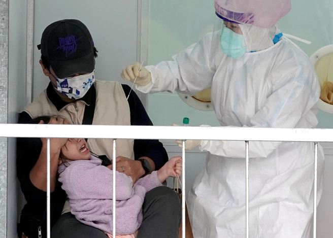 一名家長帶著小女童到桃園中路運動公園篩檢站採檢，女童掙扎哭喊抵抗，一旁的醫護人員只能耐心安撫。（黃世麒攝）