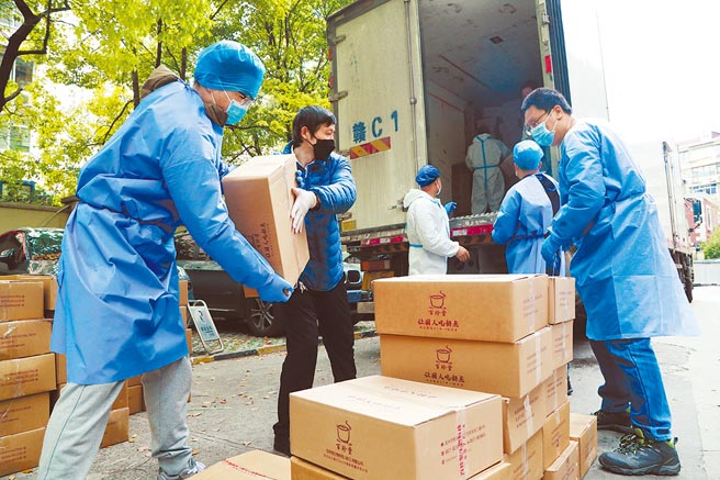 近日上海设置666家优先復工復产「白名单」，包含台商大厂如台积电、日月光、广达等。图为上海社区的工作人员18日搬运保供物资。（中新社）
