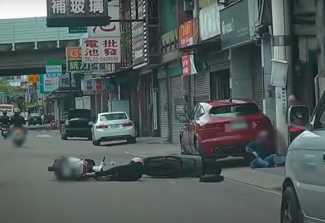 兩名機車騎士發生車禍後，痛苦地摔倒在地。（翻攝自YouTube頻道「WoWtchout - 地圖型行車影像分享平台」）