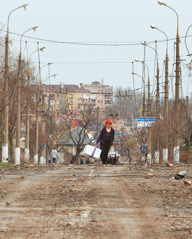 一名乌克兰民眾走在马立波市残破不堪的街道上。（路透）