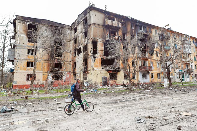 图为在马立波，当地居民走过被损坏的建筑。（路透）