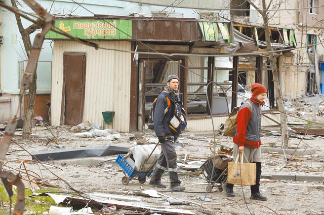 4月18日，在馬立波，當地居民走過被損壞的建築。（新華社）
