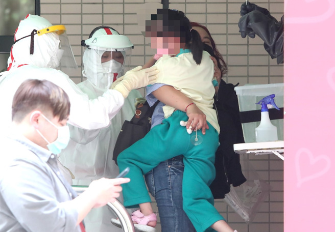 新冠肺炎疫情持續升溫，民眾帶著小朋友去篩檢站篩檢。（鄭任南攝）