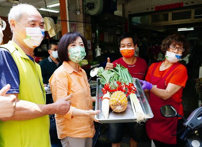 民进党立委何欣纯（左2）24日到向上市场争取民眾支持，有支持者送上凤梨，祝她成功获得徵召。（何欣纯服务处提供／张妍溱台中传真）