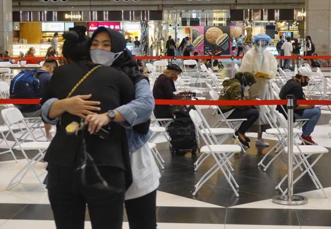 新冠疫情持續攀升，民眾施打疫苗再現熱潮，兩名外籍移工24日在台北車站準備登記施打疫苗，卻因額滿無法如願接種，兩人與工作人員交涉後，神情沮喪相互擁抱。（黃子明攝）