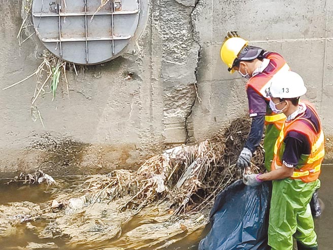 高雄市环保局办理河面巡检作业，巡检人员冒雨清理上游农田、水沟等冲刷至河道的稻秆、杂草及废弃物。（高市环保局提供／袁庭尧高雄传真）