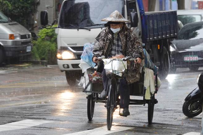 台北市25日下午突然降下陣雨，資源回收長者在雨中踩著三輪車前進。據氣象局預報資料，台北市今天氣溫最高達攝氏32度，但午後有局部短暫雷陣雨。（黃子明攝）