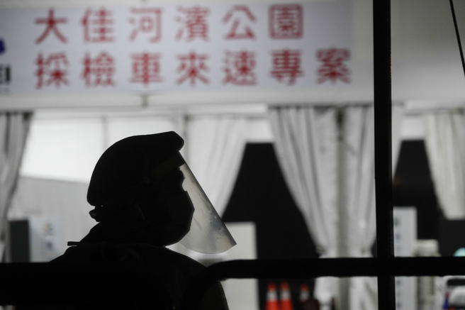 台大医曝错误戴口罩4举动，恐增加染疫风险。图为台北市大佳河滨公园车来速专案採检出口处，员警穿戴全副防疫装备站岗。（黄子明摄）

